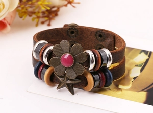 Macro detail of double-layer vintage leather bracelet with bronze floral and star charms