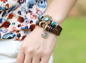 Dettaglio di bracciale vintage in pelle multistrato con fiore di bronzo e ancora