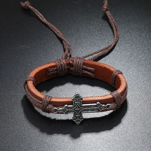 Detail of vintage braided leather bracelet with engraved cross and adjustable closure