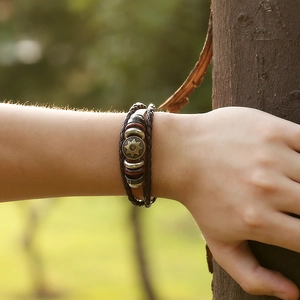 Retro multi-layer braided leather bracelet with bronze sun emblem on a natural backdrop