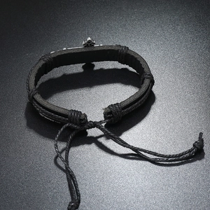 Close-up of vintage braided leather bracelet featuring an adjustable silver cross charm