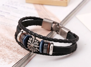 Detail of multi-layer black leather bracelet featuring vintage sunflower charm and magnetic clasp