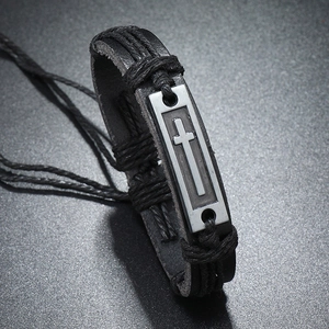 Gros plan d'un bracelet en cuir noir vintage avec une plaque métallique en croix