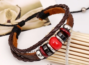 Detail of vintage multilayer braided leather bracelet with red beads on bamboo stand