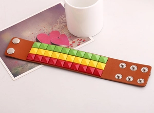 Detail view of Jamaica style wide leather bracelet with green yellow and red studs