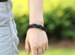 Close-up of black braided leather bracelet on wrist with a natural outdoor background