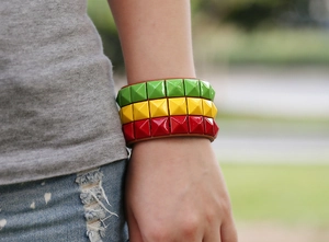Detailed close-up of Reggae style wide leather bracelet with red, yellow, green studs
