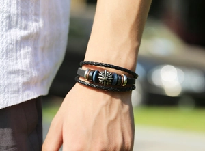 Close-up of vintage multi-layer leather bracelet with silver cross and beads on wrist