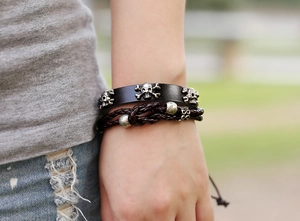 Detail shot of men's leather punk bracelet with silver skull charms and braided cord
