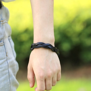 Classic black braided leather bracelet for men or women worn on wrist in outdoor setting