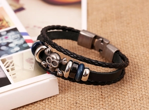 Close-up of multilayer leather bracelet with a vintage silver skull and crossbones charm