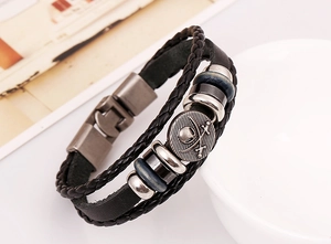 Close-up of multilayer leather bracelet featuring a vintage pirate skull metal pendant