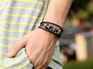 Detail view of a multi-layer punk leather bracelet with metal skull and beads on wrist