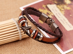 Détail d'un bracelet en cuir vintage avec étoile en métal sur fond de bambou tressé