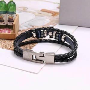 Détail d'un bracelet en cuir tressé noir avec perles argentées et fermoir aimanté