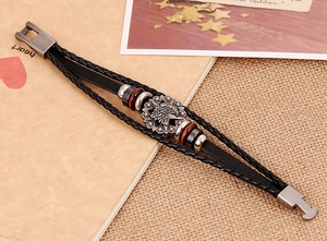 Detail of multi-layer braided leather bracelet featuring a silver eagle head relief charm