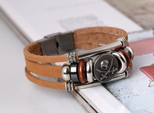 Detail of multi-layer leather bracelet featuring pirate skull charm and magnetic clasp