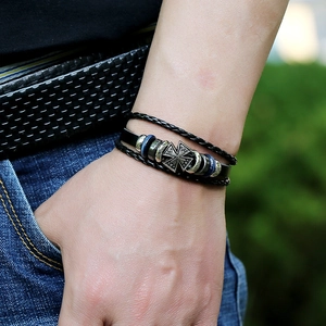 Gros plan d'un bracelet en cuir pour homme avec croix en argent et perles bleues