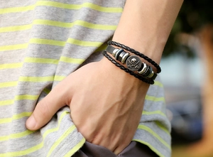 Close-up of a men's punk leather bracelet featuring a pirate skull and swords metal charm