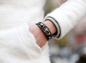 Détail d'un bracelet multicouche en cuir marron avec breloque étoile et tressage