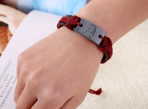 Detail of hand wearing Aquarius zodiac leather bracelet with red braided rope and metal plate