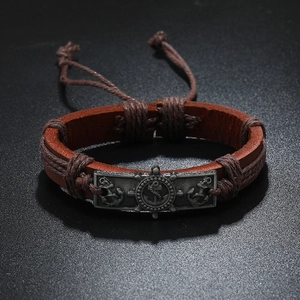 Macro view of nautical anchor and helm engraving on brown leather woven bracelet