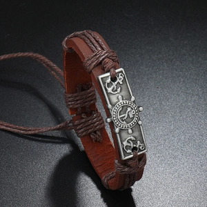 Macro view of brown braided leather bracelet featuring engraved nautical anchor metal plate