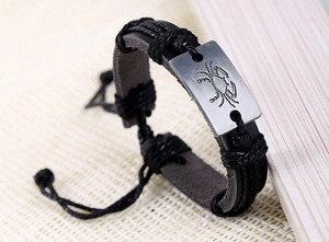 Gros plan du signe du zodiaque Cancer gravé sur un bracelet en cuir tressé noir