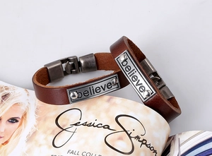 Détail d'un bracelet en cuir vintage avec plaque gravée believe sur un magazine de mode