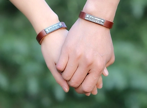 Gros plan de bracelets en cuir pour couple avec plaque en métal gravée believe