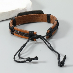 Détail du bracelet en cuir tressé à la main avec cordons réglables sur fond de pierre