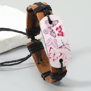 Détail du bracelet en cuir tressé marron avec plaque métallique à motif papillon