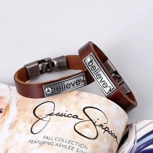 Paire de bracelets vintage en cuir marron avec plaque métallique gravée Believe sur magazine