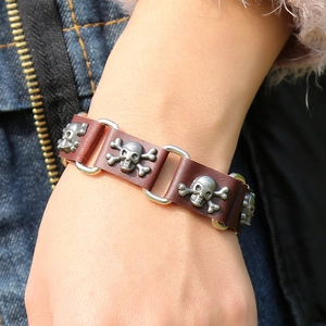 Detail of dark brown leather punk bracelet featuring vintage silver skull and crossbones studs