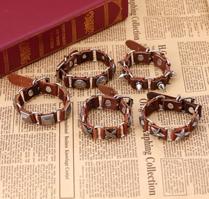 Set of five vintage brown leather punk bracelets with silver alloy buckles on newsprint