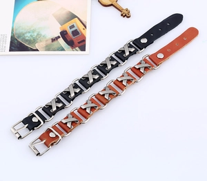 Detail of adjustable leather bracelets with silver X-shaped metal studs and buckle closure