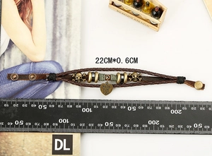 Detail of multi-layer braided leather bracelet with skull charms and heart pendant