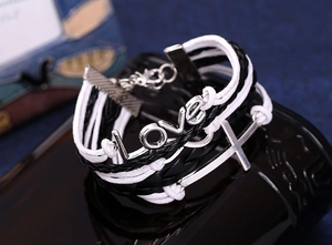 Close-up of multilayer leather bracelet with LOVE metal charm and silver cross detail