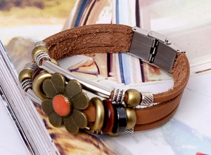 Macro view of brown multi-layer leather bracelet featuring daisy pendant and steel clasp