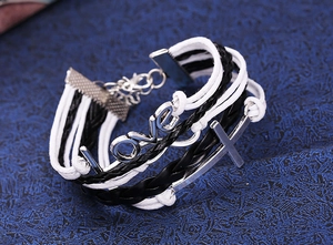 Detail of layered woven leather bracelet with silver LOVE letters and cross charm