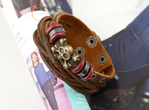 Détail du bracelet vintage en cuir marron avec crâne en métal et boutons-pression réglables