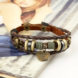 Vintage multi-layer leather bracelet with bronze skull and heart charm on a magazine
