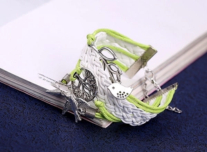 Gros plan d'un bracelet tissé boho avec breloques arbre de vie et oiseau en argent