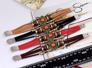 Detail of vintage leather bracelet set with sunflower charms and antique metal beads