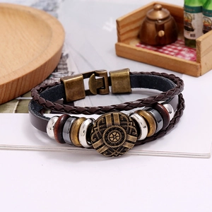 Close-up of vintage multi-layer braided leather bracelet with bronze wheel charm