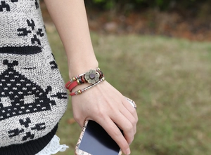 Detail of a vintage layered leather bracelet with a bronze sunflower and red gemstone