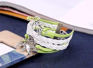 Détail d'un bracelet tressé avec breloques feuille, arbre de vie et oiseau