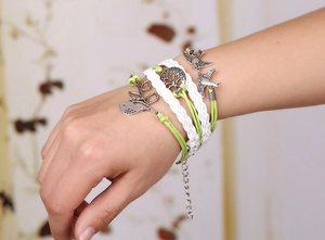 Détail d'un bracelet tissé multicouche avec arbre de vie et breloques oiseau au poignet