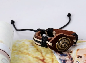 Détail d'un bracelet en cuir marron fait main avec rose en bronze et cordons tressés