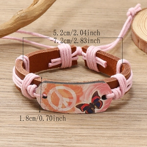 Handmade woven leather peace sign bracelet with butterfly print on wooden background